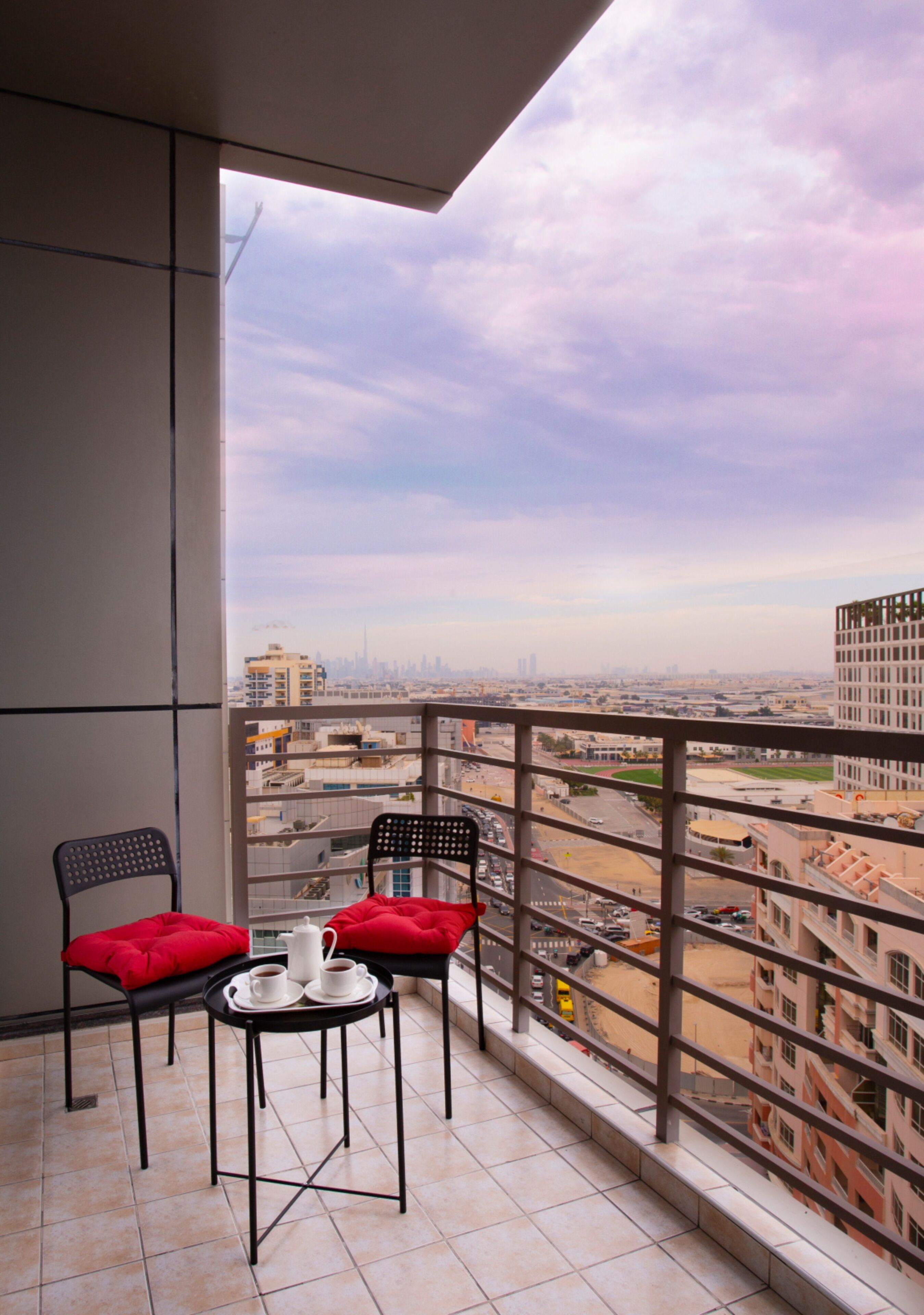 A balcony with two chairs and a small table, offering a city view.