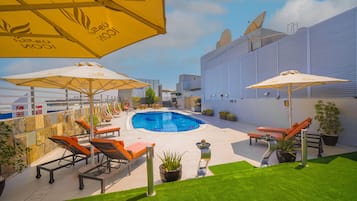 Una piscina al aire libre, sombrillas, sillones reclinables de piscina
