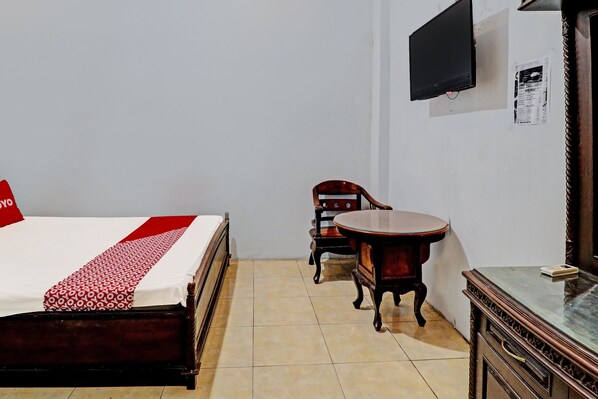 A hotel room with a bed, a wooden chair, a small round table, a TV mounted on the wall, and a cabinet. - OYO 2452 Hotel Metro (Jawa Barat)