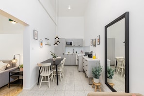 Una cocina moderna con armarios blancos, una mesa de comedor con sillas y un espejo grande.