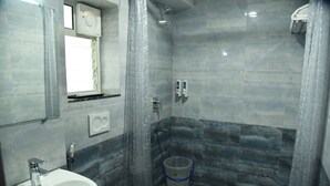 A bathroom with a sink, toilet, shower, and a small trash bin. - The Altruist New Town Hotel (Barasat)