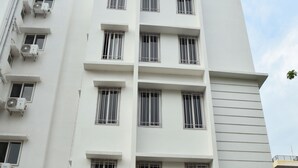 A multi-story building with a modern design, featuring a central entrance with glass doors and a sign above. - The Altruist New Town Hotel (Barasat)
