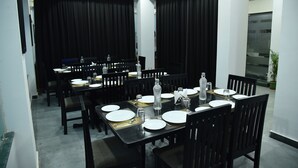 A conference room with multiple tables set for a meeting, equipped with water bottles, glasses, and plates. - The Altruist New Town Hotel (Barasat)