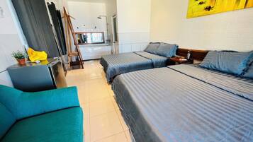 Habitación de hotel con dos camas, un sofá, un cuadro en la pared y un baño visible a través de una puerta abierta.
