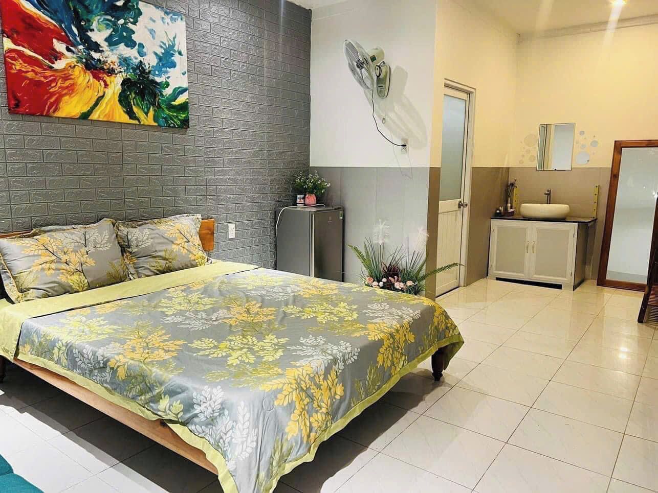 A bedroom with a bed, a dresser, a mirror, and a wall-mounted fan.