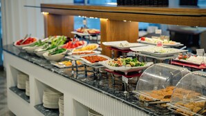 Buffet com diversos alimentos e um expositor de vidro.