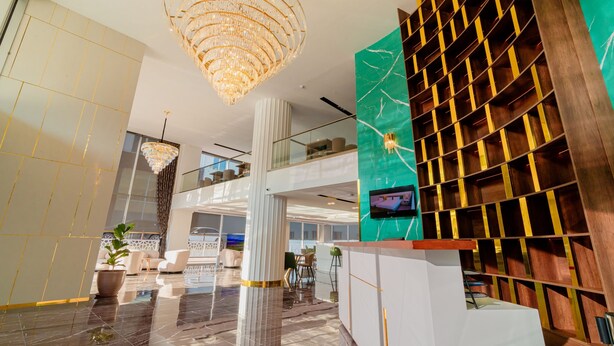 Um lobby moderno com um candelabro, um balcão de recepção e uma área de estar com cadeiras e um sofá.
