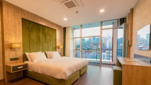 Quarto de hotel moderno com uma cama grande, uma escrivaninha e vista para a cidade.