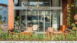 Café e restaurante com mesas ao ar livre e vista para a cidade.