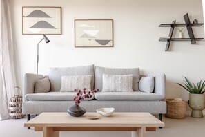 A living room with a grey sofa, a wooden coffee table, and two framed abstract artworks on the wall.