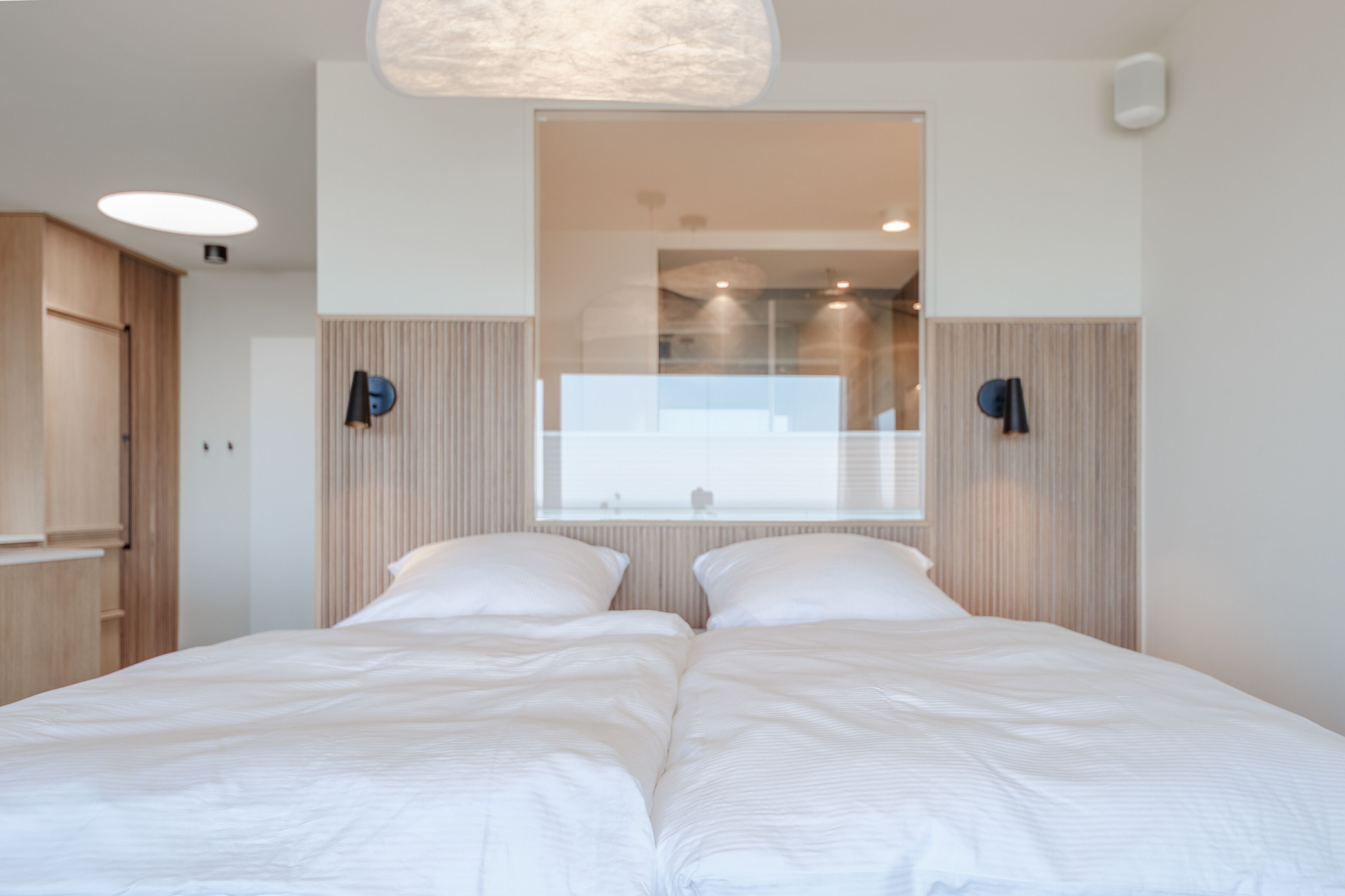 Un dormitorio moderno con una cama grande, un armario empotrado y un ventanal con persianas.