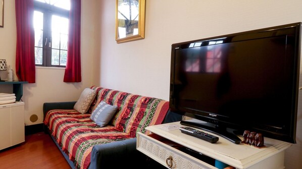 Una habitación acogedora con un sofá, un televisor y un control remoto sobre una mesita.