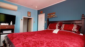 Una habitación de hotel con una cama grande, televisión, armario y puerta.