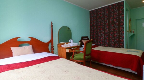 Ein Hotelzimmer mit zwei Betten, einem Schreibtisch, einem Stuhl und einem Spiegel.