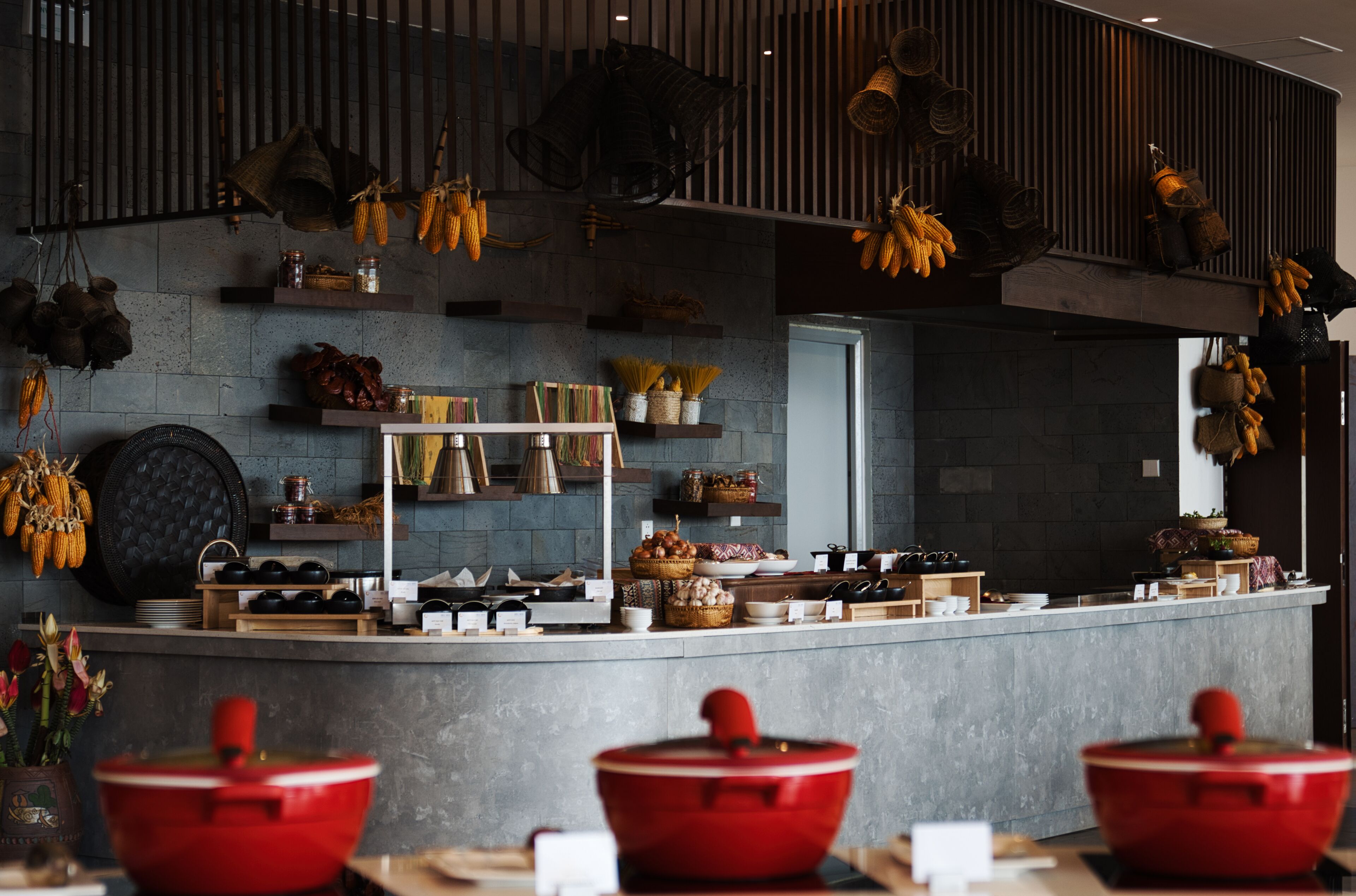 A modern kitchen with a central island, hanging utensils, and various kitchenware.