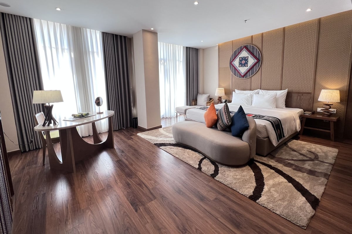 Ein Hotelzimmer mit Bett, Sofa, kleinem Tisch und Schreibtisch.