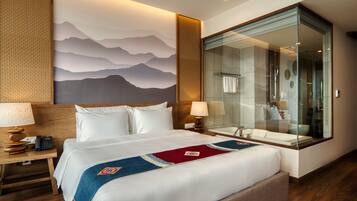 Una habitación de hotel con una cama grande, ducha con cerramiento de vidrio y un mural en la pared.