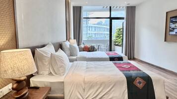 Hotellihuone, jossa on kaksi sänkyä, puinen yöpöytä, lamppu ja näkymä rakennukseen suurista ikkunoista.
