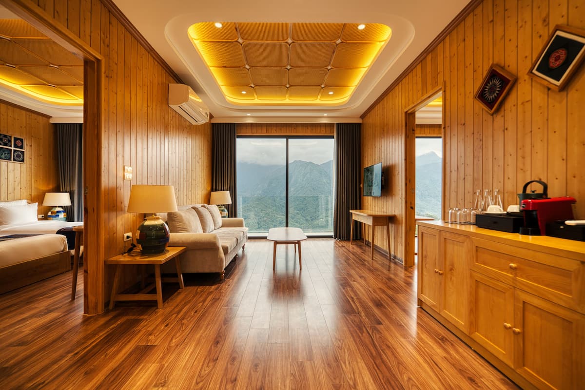 Ein Hotelzimmer mit Holzvertäfelung, einem Bett, einem Sofa, einem Couchtisch, einem Fernseher und Bergblick.