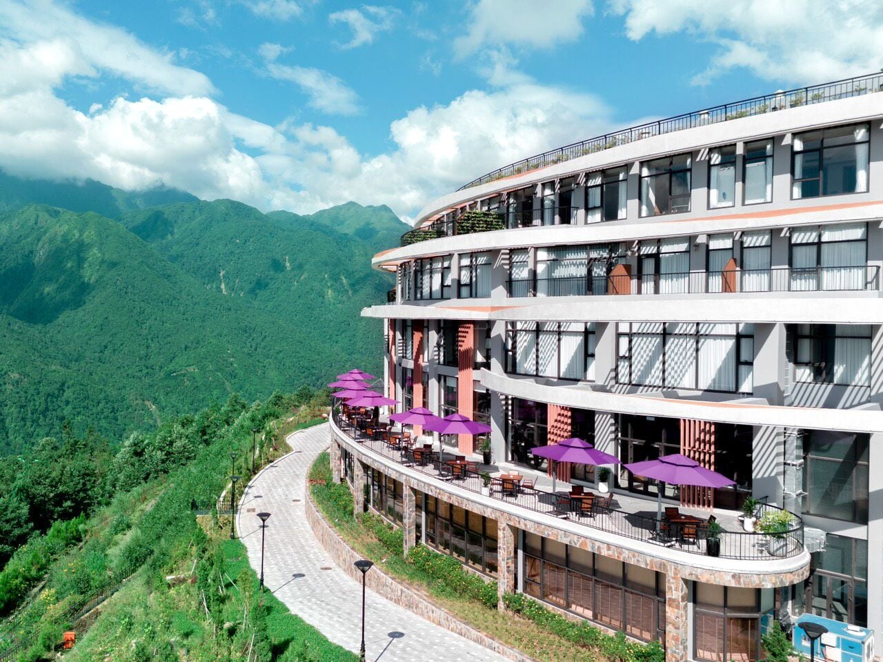 A multi-story hotel with outdoor seating and mountain views.