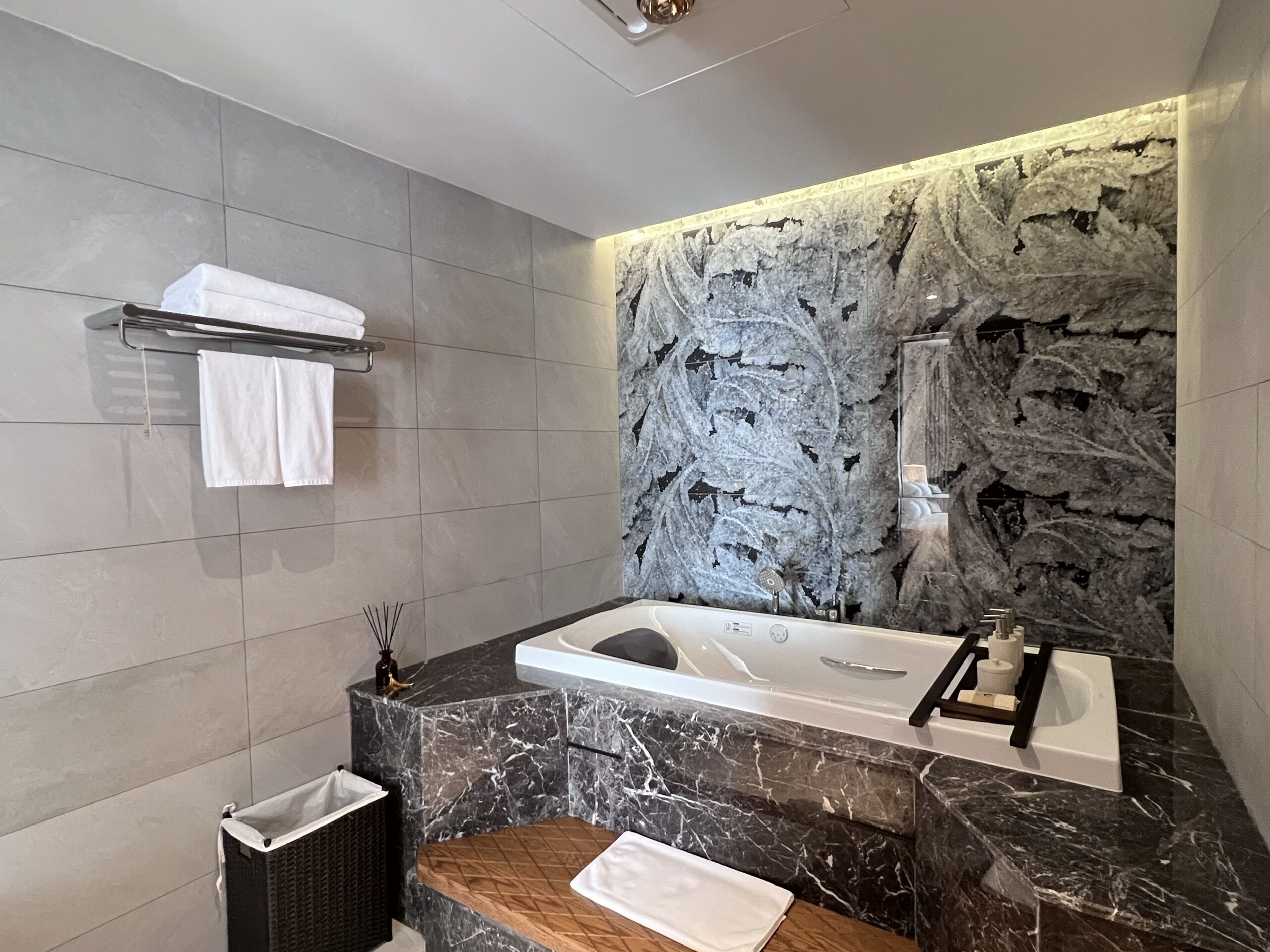 Une salle de bain moderne avec un lavabo en marbre, une baignoire et un mur en pierre.