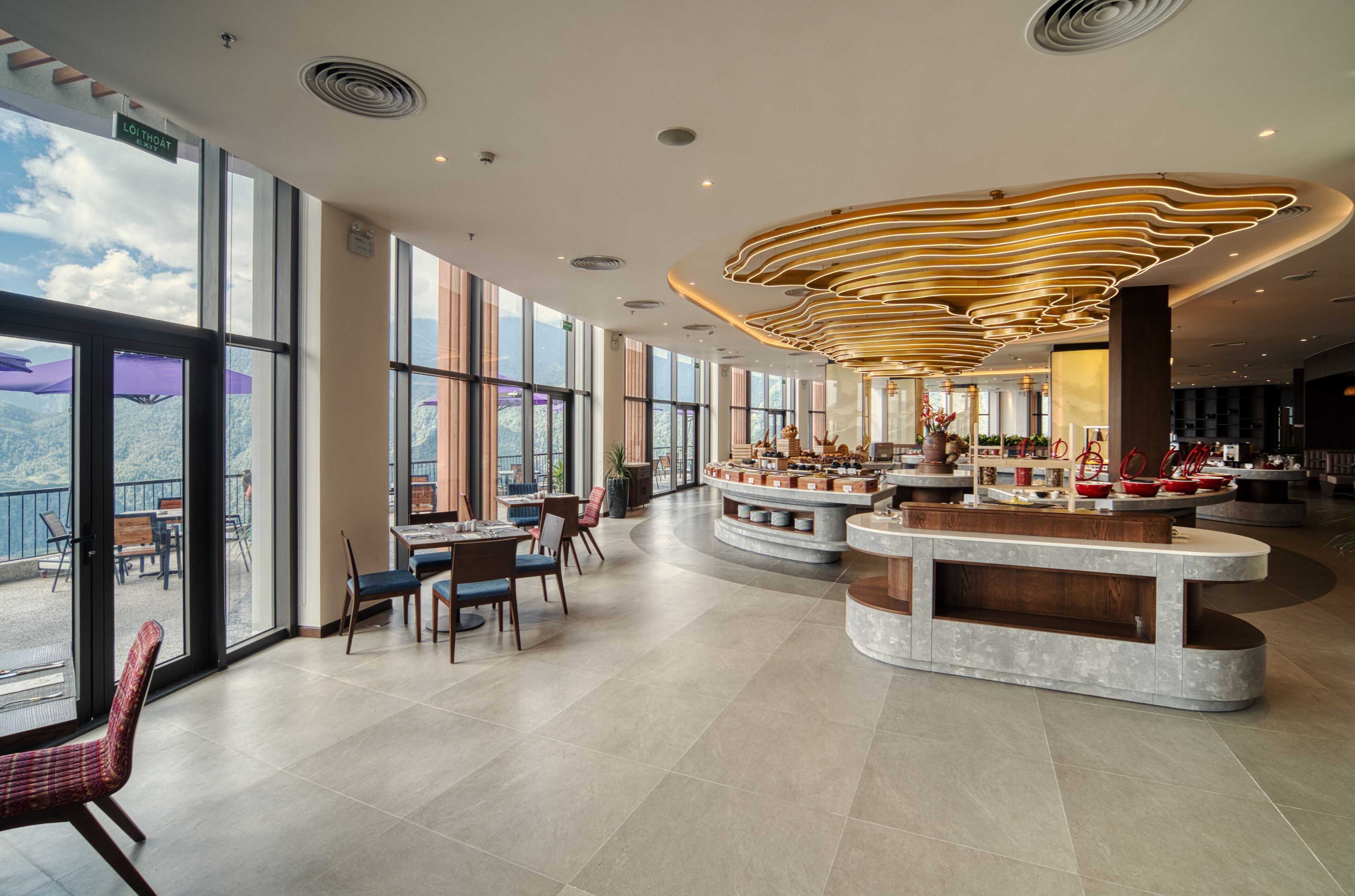 A spacious lobby with large windows, a central seating area, and a modern ceiling design.