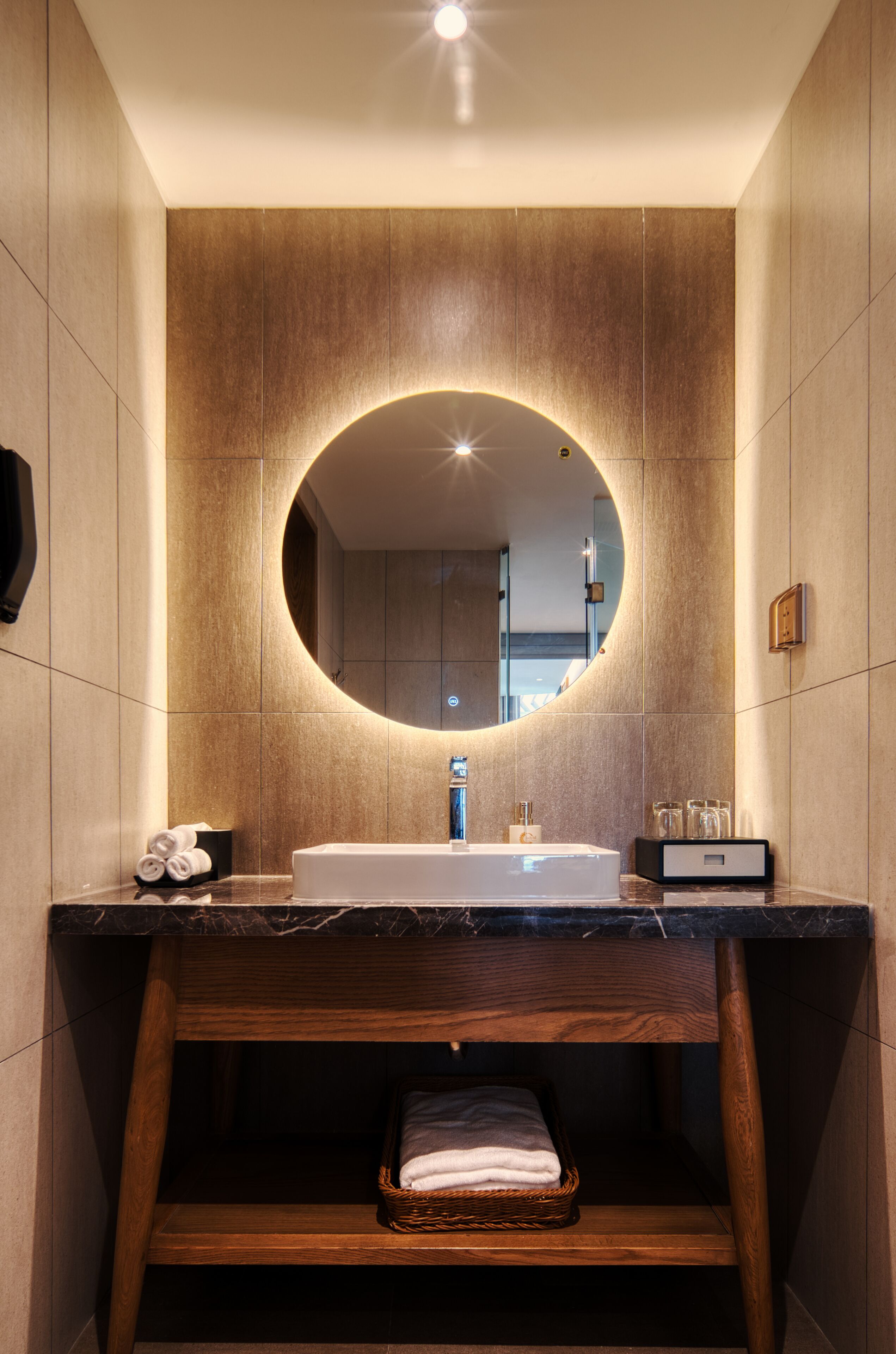 Een moderne badkamer met een grote spiegel, een houten wastafelmeubel en een inbouwkast.