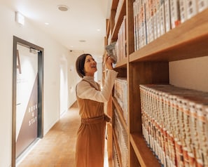 A person browsing books in a library with a 'BOOK & STAY' sign on the wall. - RELIEF KOKURA ANNEX Book & Stay (Kitakyushu)