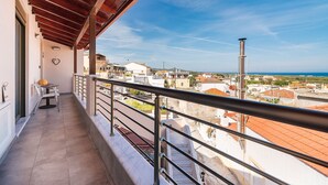 A balcony with a view of the sea, a table with chairs, and a heart-shaped decoration.