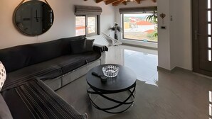 A modern living room with a sectional sofa, a round coffee table, a wall clock, and a wooden ceiling.