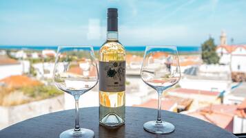 Una botella de Sauvignon Blanc y dos copas sobre una mesa con vista a edificios y al mar.