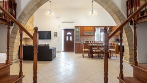 A spacious living area with a wooden staircase, a dining area, and a kitchen visible through an archway. - Villa 'Nikolaos' with Sea View, Wi-Fi and Air Conditioning (Rhodes)