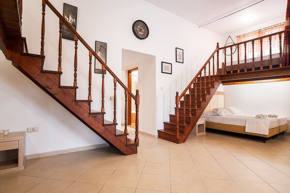 A staircase with wooden balusters, a bed with white linens, and a wall clock.
