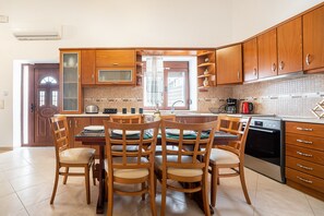 A kitchen with wooden cabinets, a dining table with chairs, and a built-in oven.