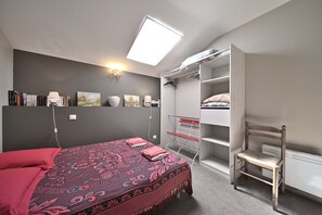 Une chambre à coucher comprenant un lit, un bureau, une chaise, une armoire et une fenêtre de toit.