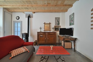 A living room with a sofa, a red table, a wooden cabinet, a television, and a fireplace.