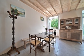 Un espace repas comprenant une table en bois, des chaises, un banc et un buffet.
