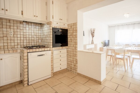 Une cuisine avec des meubles blancs, une cuisinière noire et un lave-vaisselle.