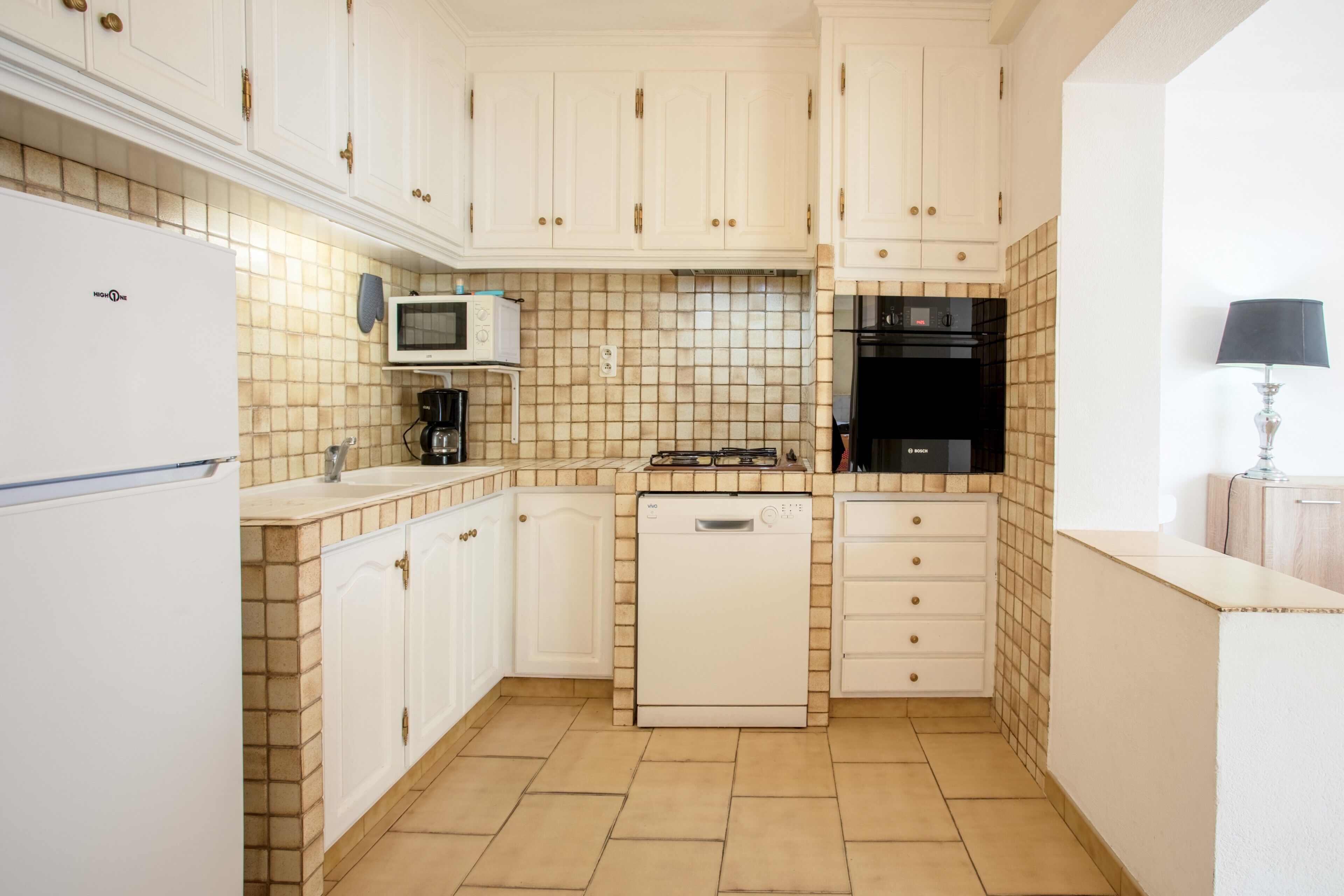 A compact kitchen with white cabinets, a microwave, a dishwasher, and a stove.