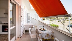 A balcony with a table and chairs, a sliding glass door, and a view of the street. - Holiday Home 'A Due Passi dal Mare' with Sea View, Wi-Fi and Air Conditioning (Porto Cesareo)