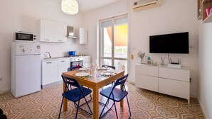A compact kitchen with a dining table, chairs, a TV, and a window with a view. - Holiday Home 'A Due Passi dal Mare' with Sea View, Wi-Fi and Air Conditioning (Porto Cesareo)
