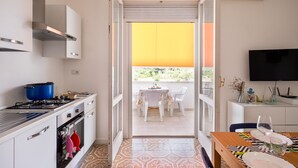 A kitchen with a stove, oven, and a dining area with a table and chairs. - Holiday Home 'A Due Passi dal Mare' with Sea View, Wi-Fi and Air Conditioning (Porto Cesareo)
