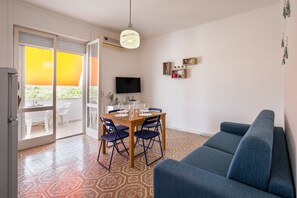 Une pièce comprenant une table à manger, des chaises, un canapé, un téléviseur et un sol à motifs.