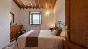 Un dormitorio con cama, cómoda de madera, ventana con vistas y techo de madera.