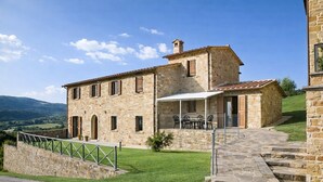 A stone building with a patio, outdoor seating, and a view of the countryside. - Apartment "Pugnano Alto - Tartufo" with Shared Pool and Wi-Fi (lisciano niccone)