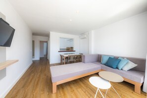 A modern living room with a sofa, a small table, and a TV mounted on the wall.