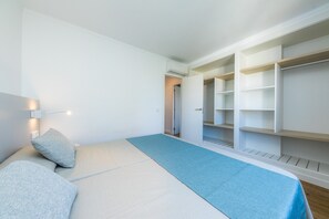 A bedroom with a bed, a blue area rug, and a walk-in closet.