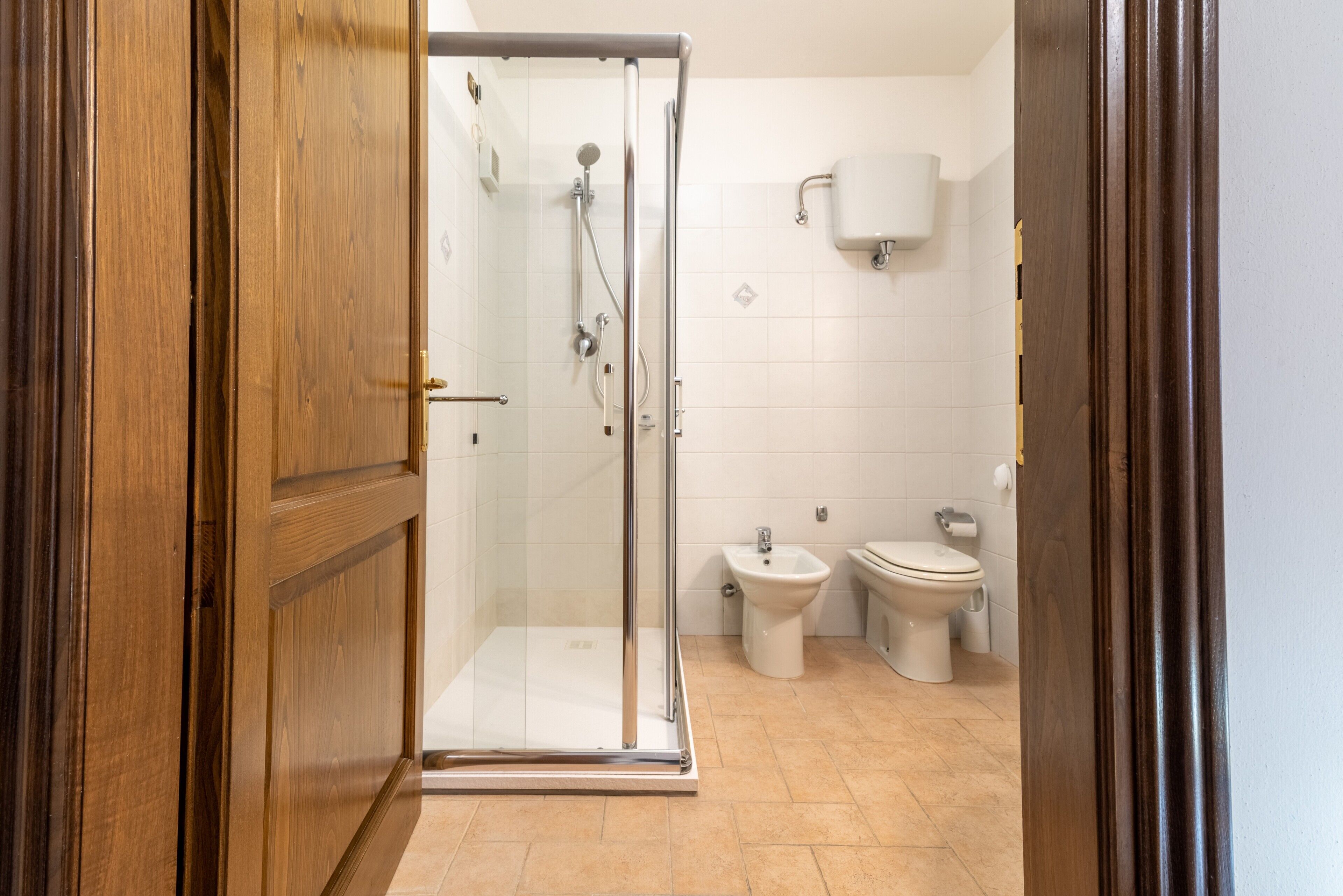 Un baño con cabina de ducha de vidrio, un bidé y un inodoro.