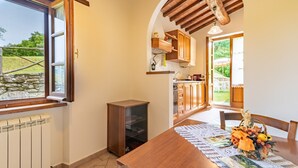 A kitchen with wooden cabinets, a dining table with a placemat, and a view of the outdoors. - Apartment "Pugnano Alto - Grano" with Shared Pool and Wi-Fi (Lisciano Niccone)
