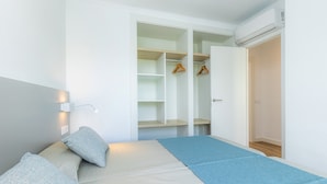 Ein Zimmer mit Bett, Kleiderschrank und offener Garderobe.
